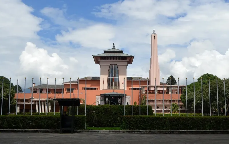 A pink palace with a tall pagoda-roofed tower and a slender spire, under a blue sky