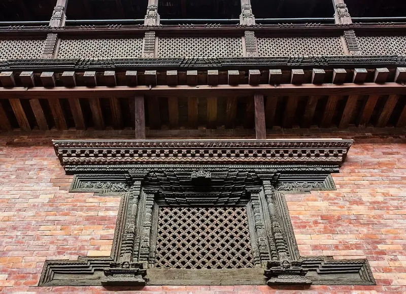 A carved wooden lattice window set in a red brick wall