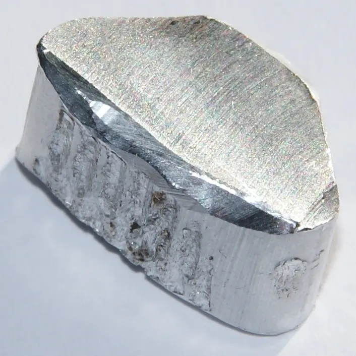 A chunk of silvery metal with a flat, finely scratched top and rough, dented sides