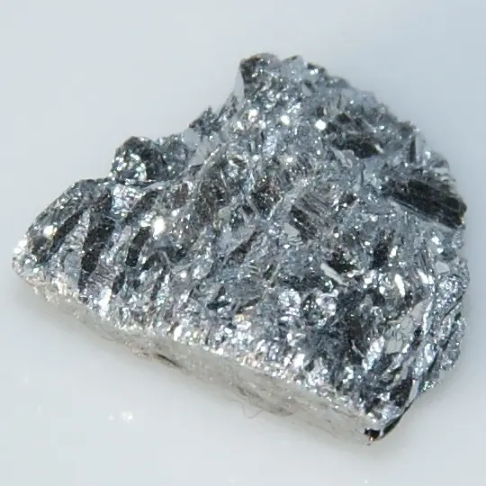 A lump of bright, silvery-gray metal covered in flat, glittering crystal faces, on a white background