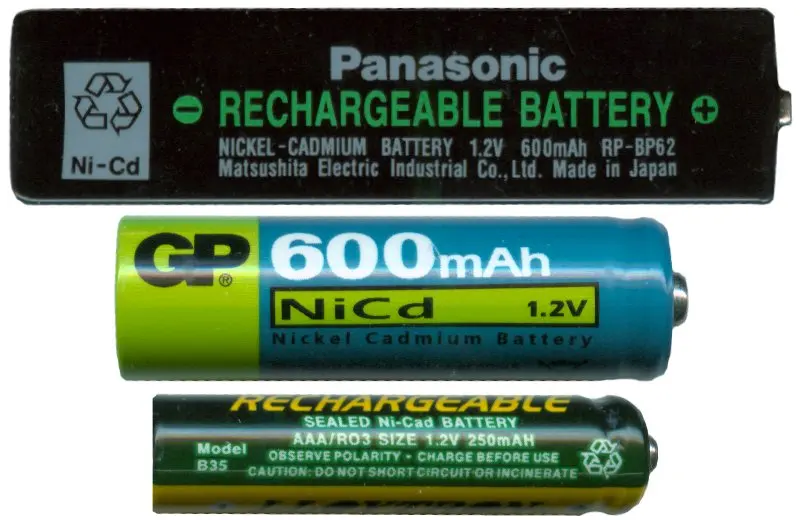 Three rechargeable batteries one above the other: a flat black stick labeled nickel-cadmium battery 1.2 V, a blue and green AA cell labeled NiCd 1.2 V, and a thin dark green AAA cell