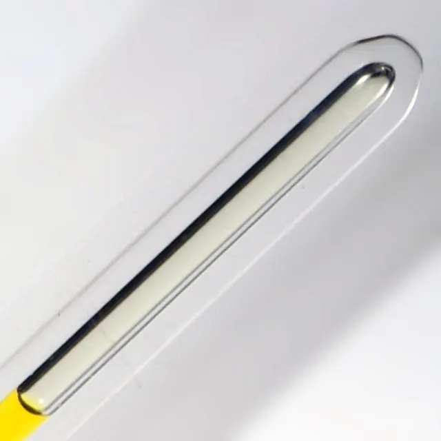 A thin sealed glass tube lying at an angle, holding a pale yellow-green liquid