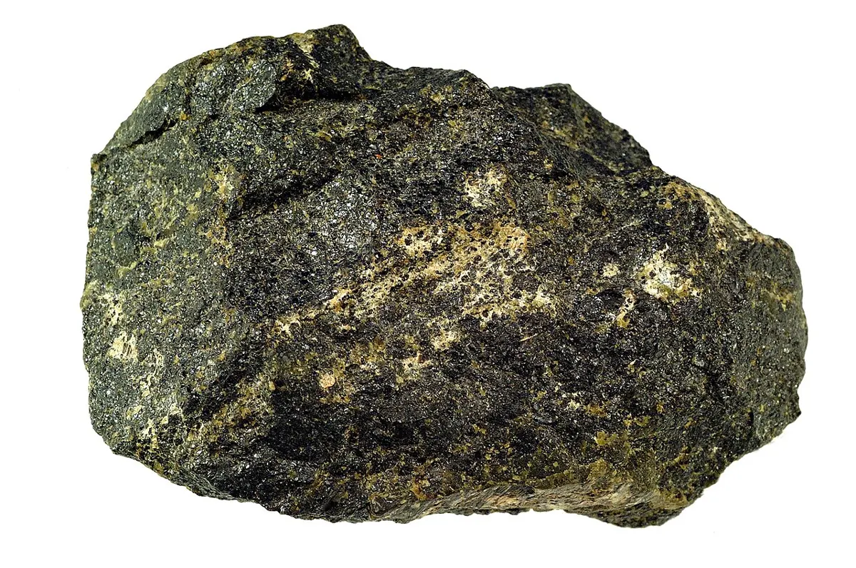 A rough, dark gray-black rock with a dull sparkle, flecked with pale yellow-green and cream patches