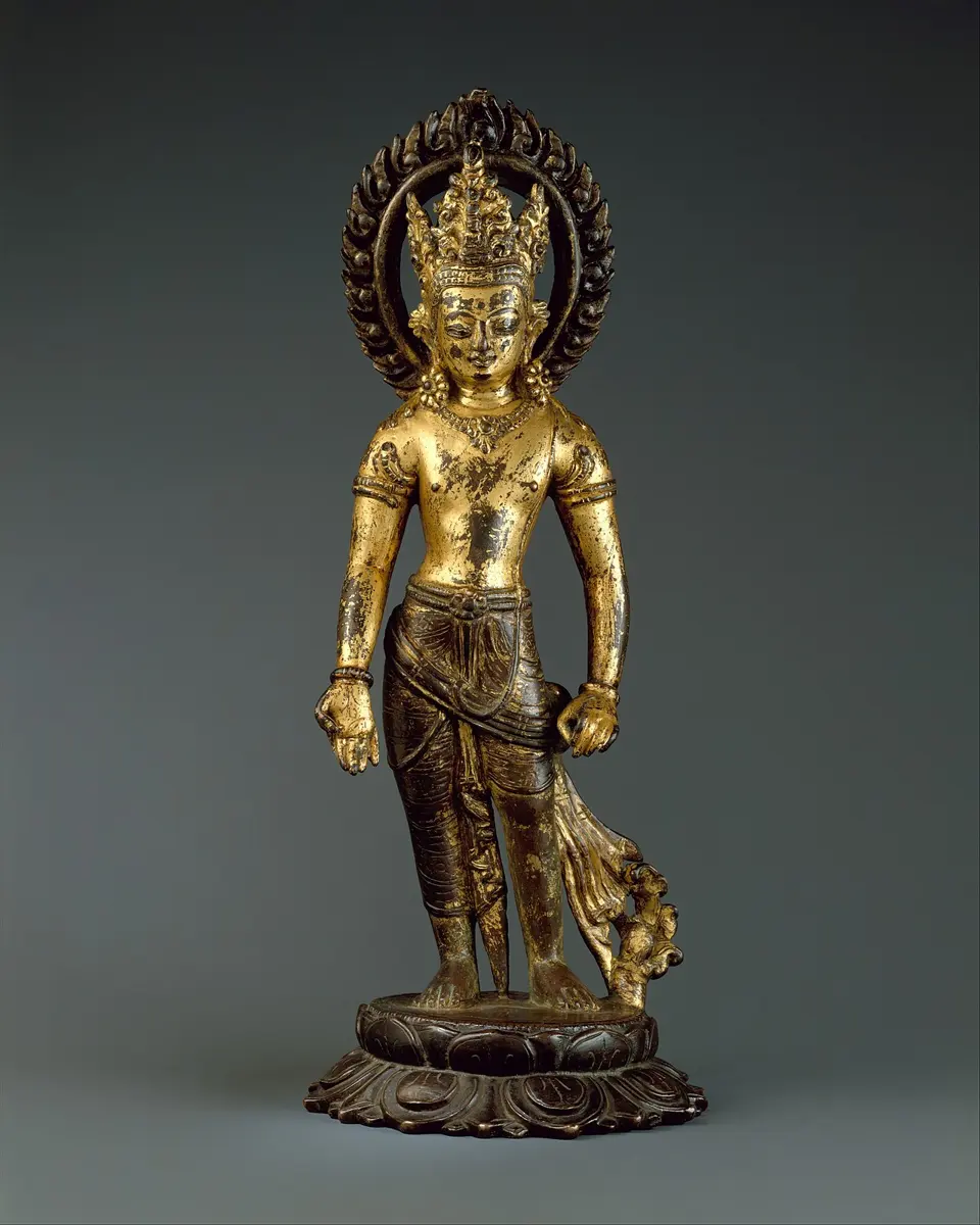 A small gilded statue of a standing figure with a crown and a flaming halo, on a lotus base; where the gold has worn away, the dark metal underneath shows
