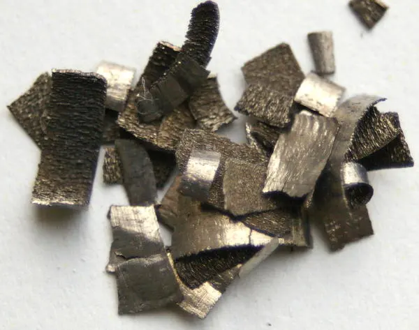A pile of small, thin, crumpled flakes of metal, gray with a brown tinge on some faces