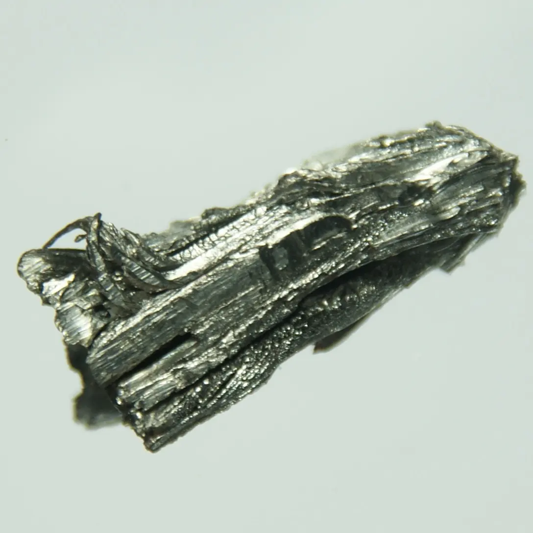 Dark gray, shiny metal crystals like a bundle of long, flat, twisted blades