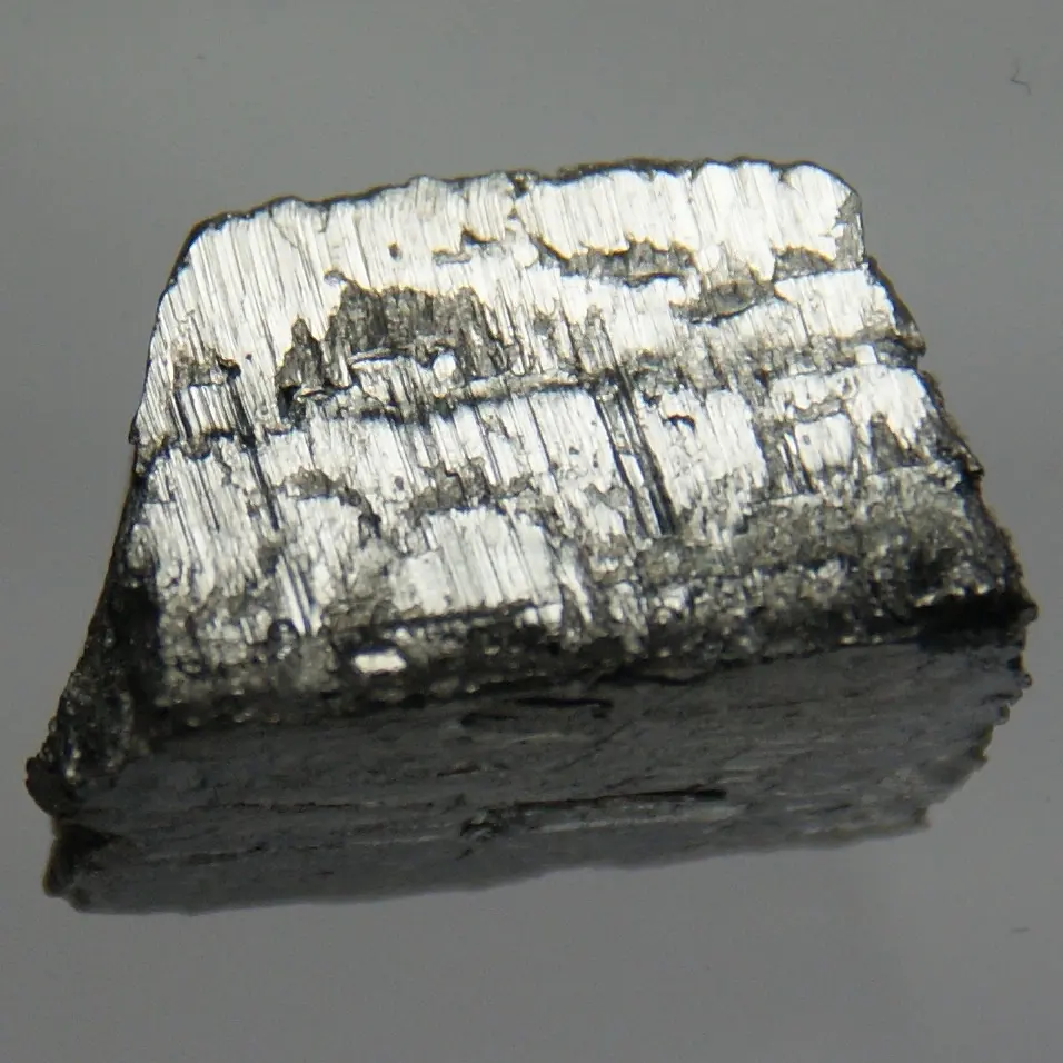 A rough block of silvery metal, shiny and finely ridged on top, darker on its sides