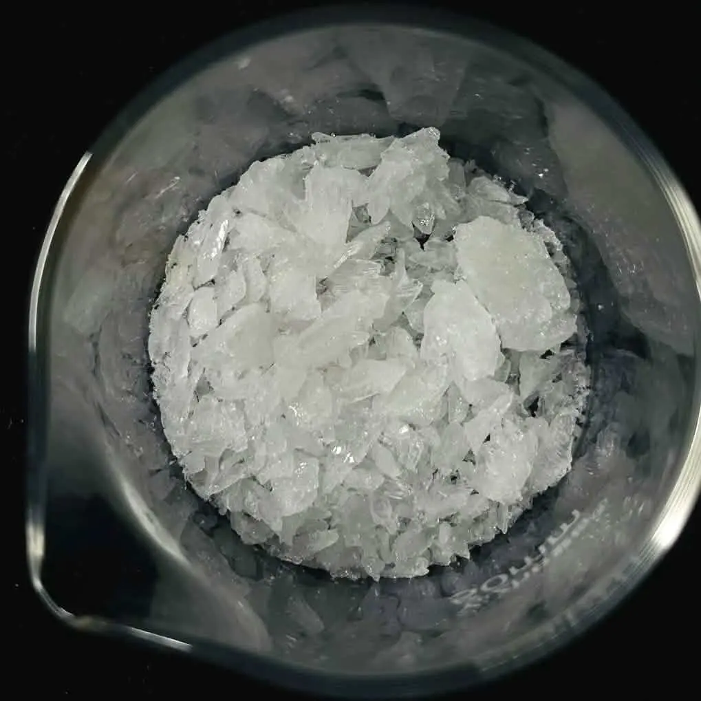 A glass beaker holding a pile of clear, glassy, colorless crystals