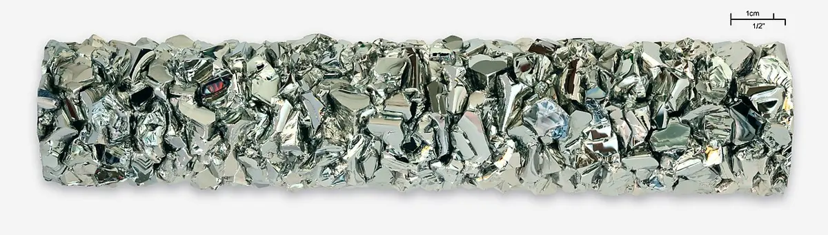 A long bar of bright, silvery metal made of hundreds of small, shiny crystals packed tightly together
