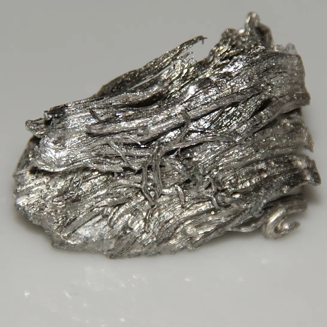A flat, shiny silver-gray piece of metal covered in wavy, layered crystal ridges