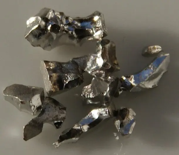 Several small, jagged, shiny silver pieces of metal scattered on a gray surface