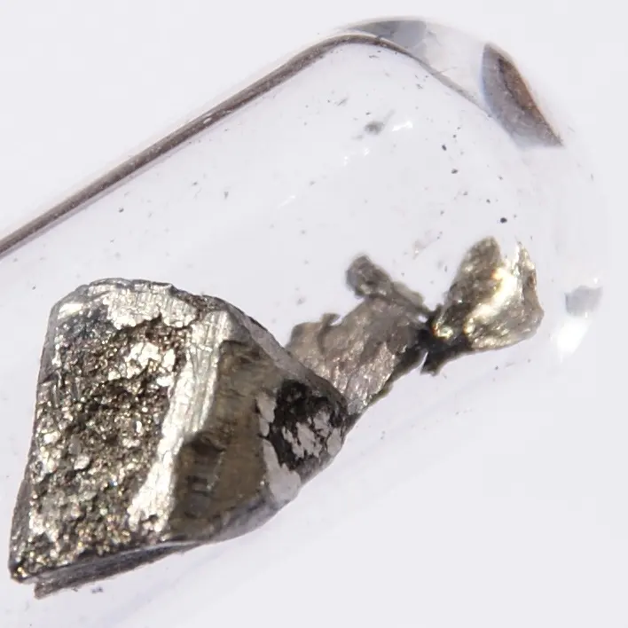 Two rough lumps of silvery-gray metal, dull and darkened in places, sealed in a clear glass tube