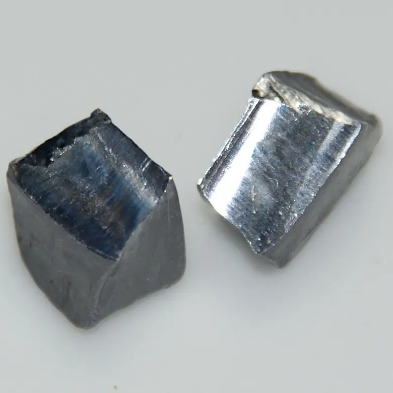 Two small gray blocks of metal on a white surface: the right one has a bright, silvery cut face, the left one has gone dark and dull