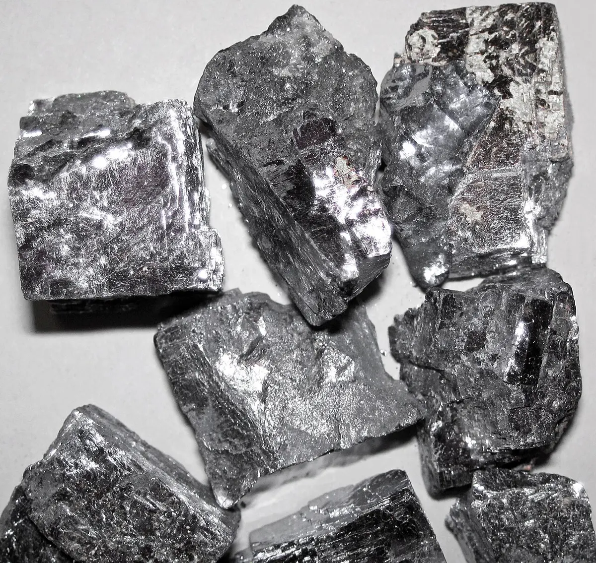 Several blocky, silvery-gray lumps with flat, shiny faces and square corners, piled on a white surface