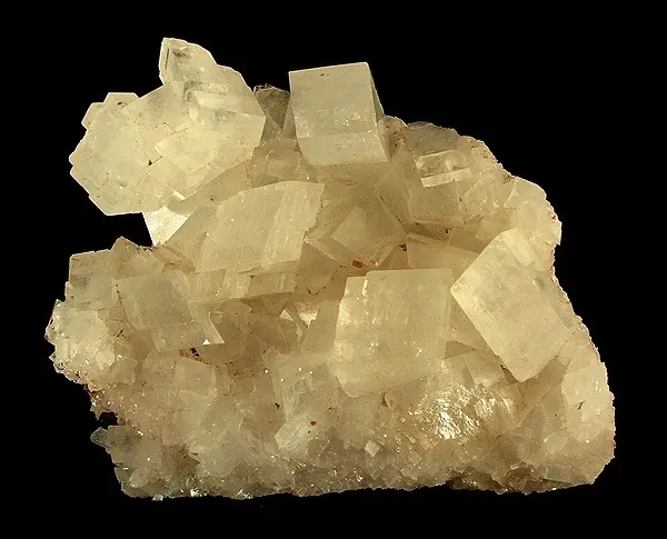 A cluster of pale cream, blocky crystals against a black background