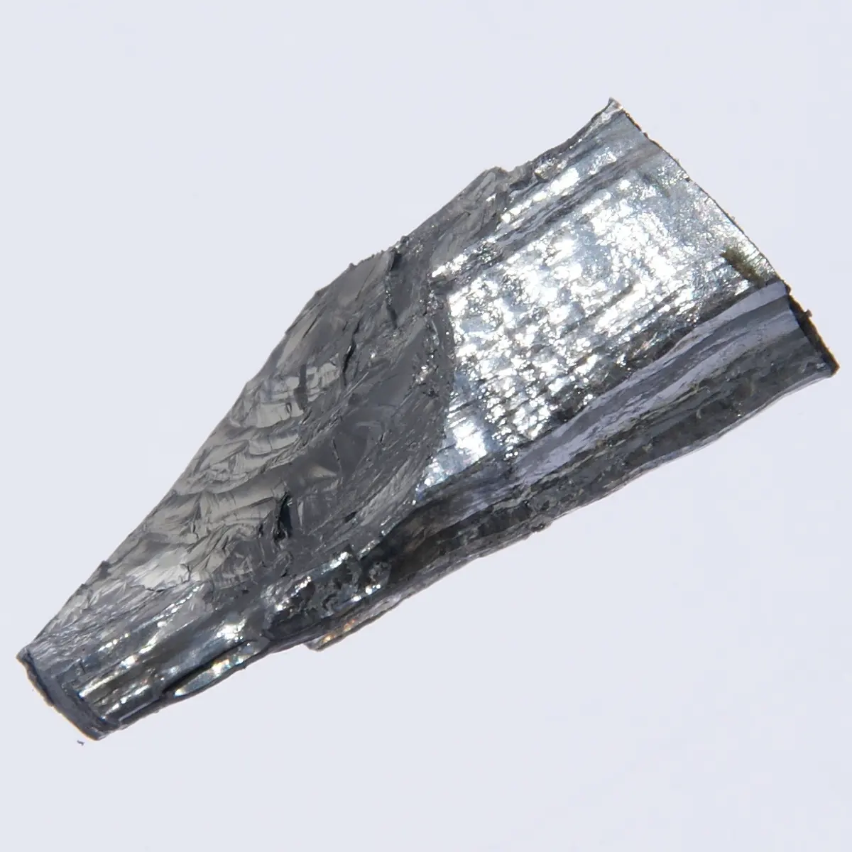 A tapering piece of shiny, silvery-gray metal with a rough, wavy surface