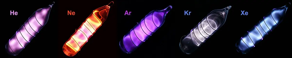 Five small glass vials in a row, labeled He, Ne, Ar, Kr and Xe, glowing pink, orange-red, violet, white and pale blue