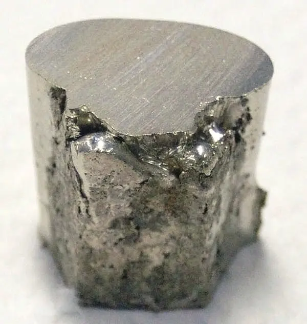 A short, chunky cylinder of silvery metal with a smooth, sawn top and rough, broken sides