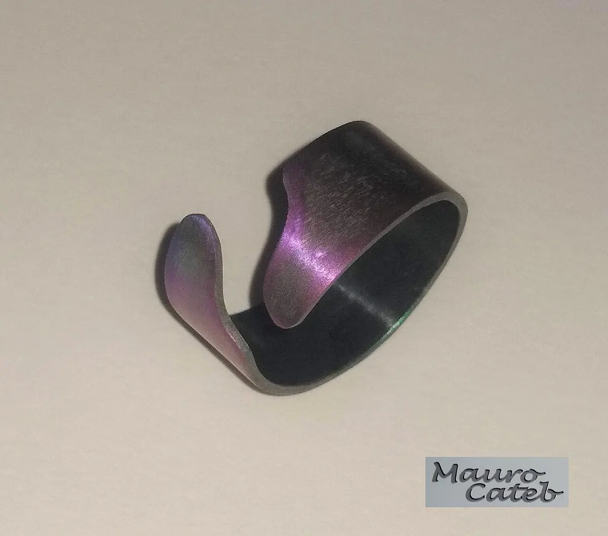 An open ring of metal, purple and dark violet, with a hint of green at one edge