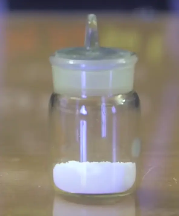 A small glass jar with a glass stopper, holding a little white powder at the bottom