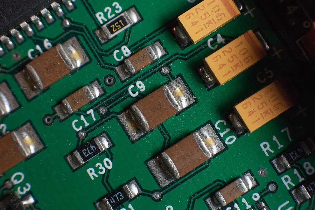 A close-up of a green circuit board with small brown blocks that have shiny metal ends, labeled C8, C9 and C10, beside yellow and black parts