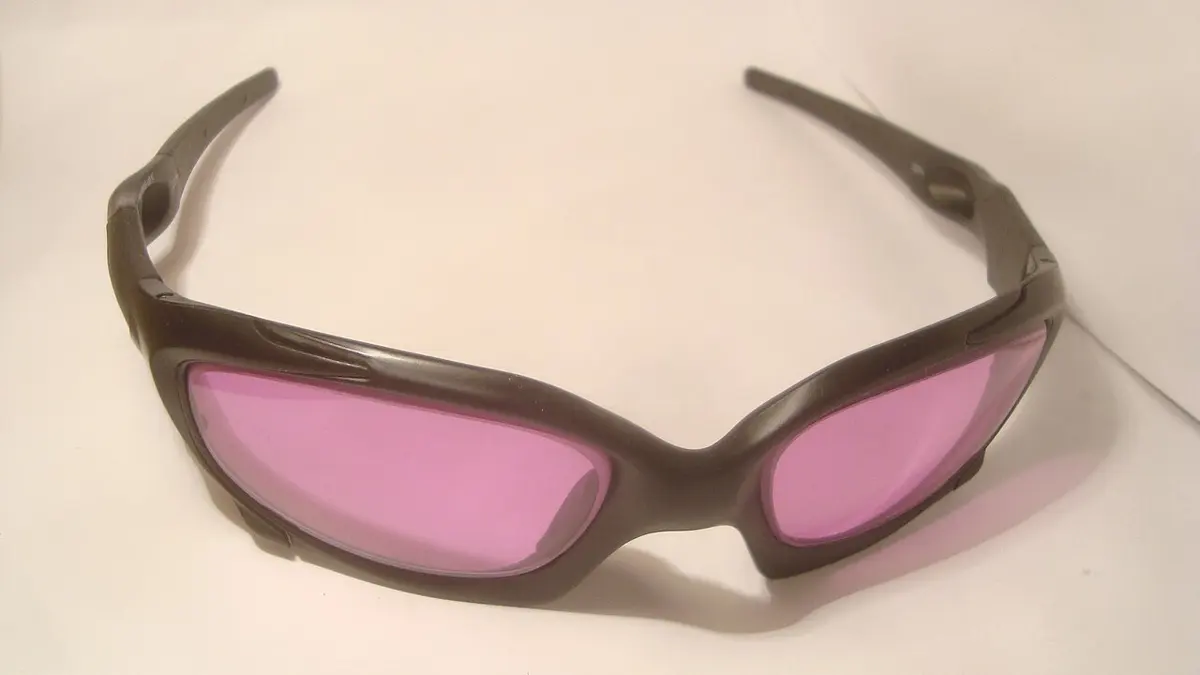 Wraparound safety glasses with a black frame and pale pink lenses