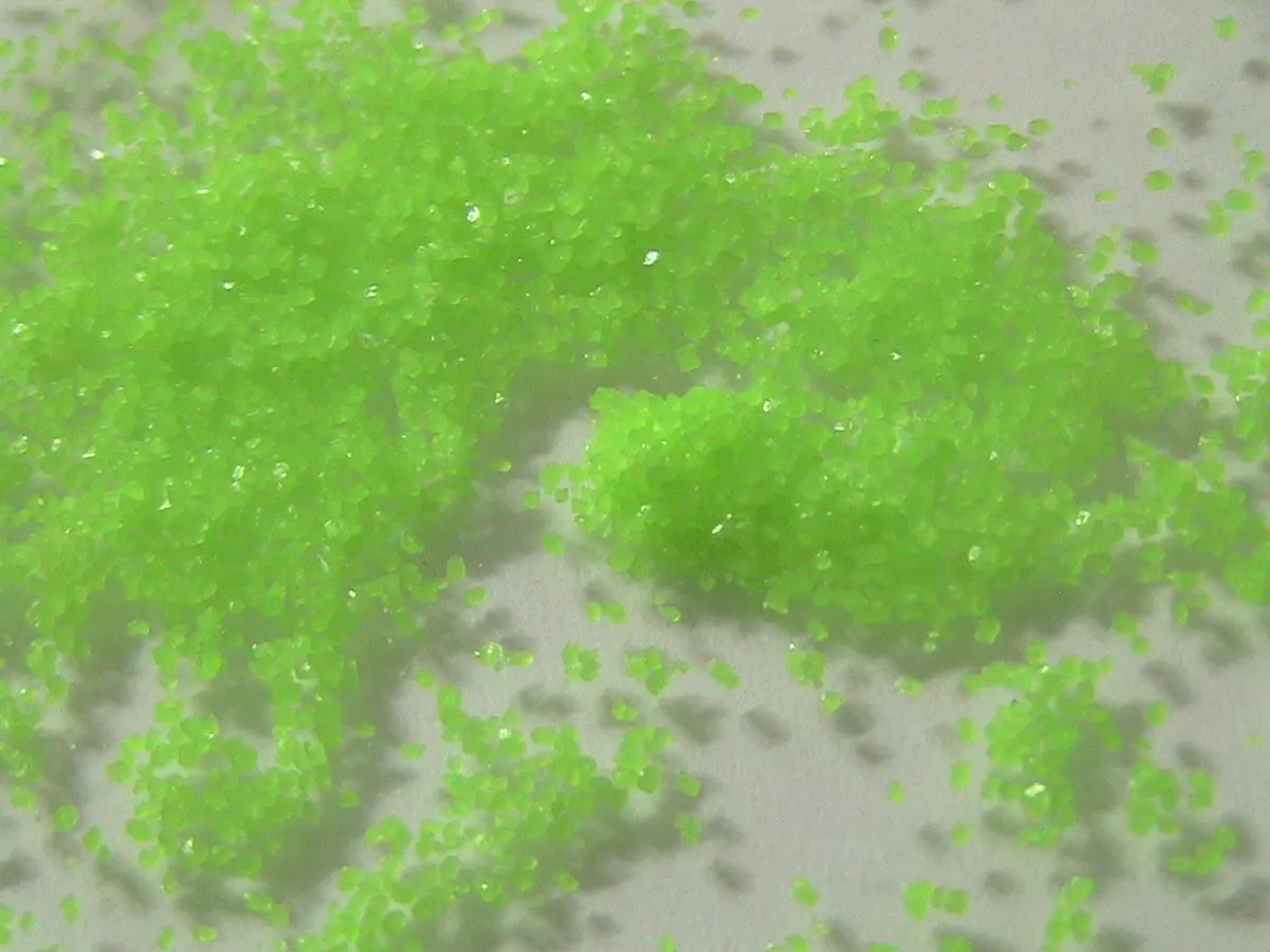 Small bright green grains, like coarse sugar, scattered on a white surface