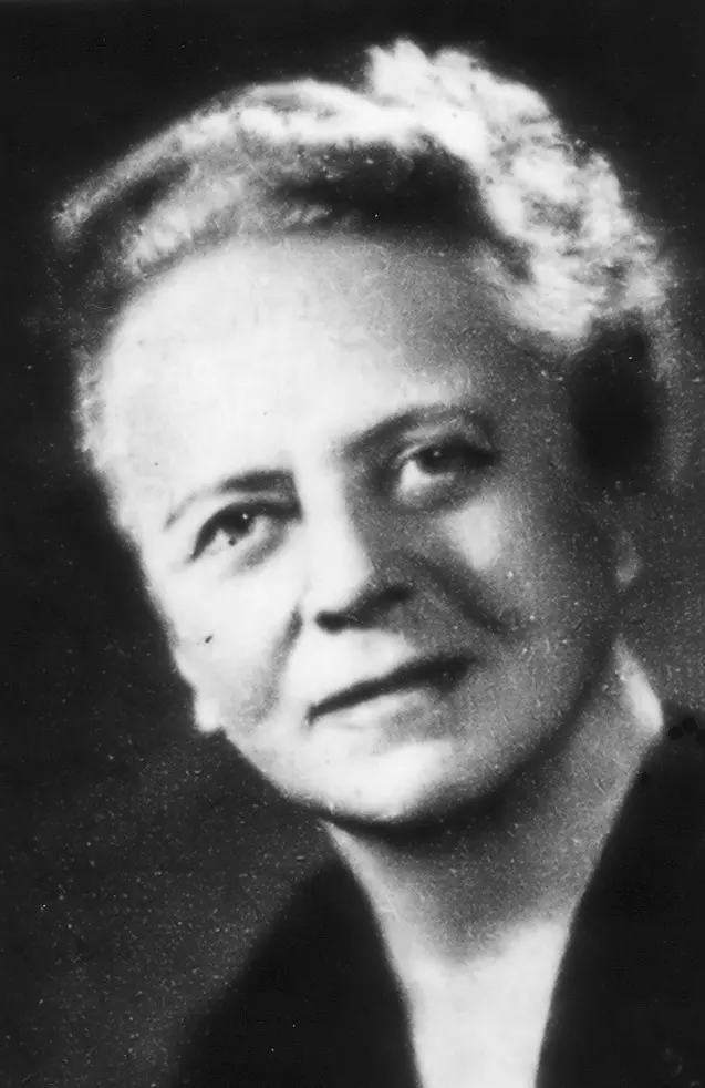 A black-and-white portrait of a woman with short, wavy gray hair, looking slightly to one side
