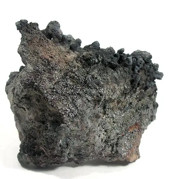 A rough, dark gray lump of volcanic rock with knobbly edges, its surface glittering with tiny silvery flakes