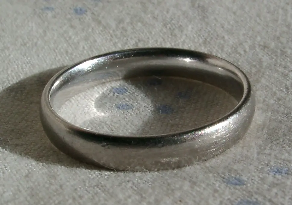 A plain, smooth, silvery-white ring lying on a pale cloth