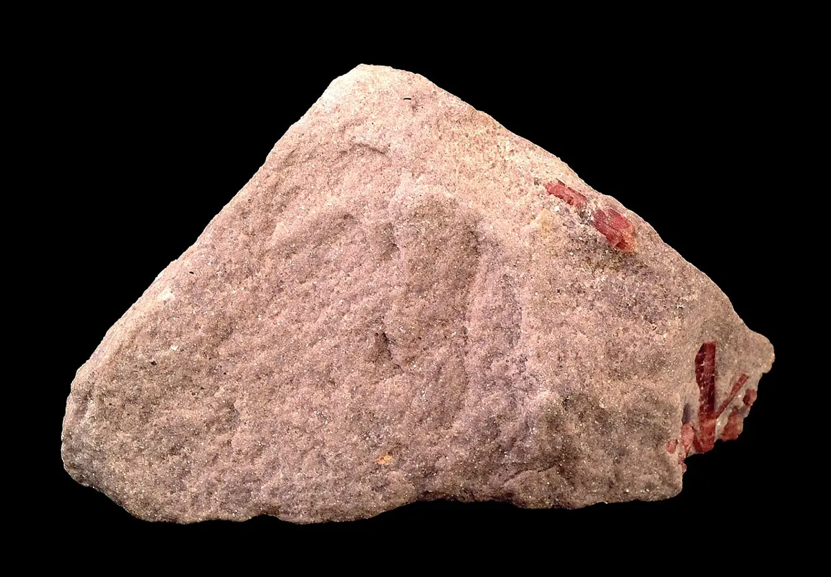 A rough, pinkish lump of rock on a black background