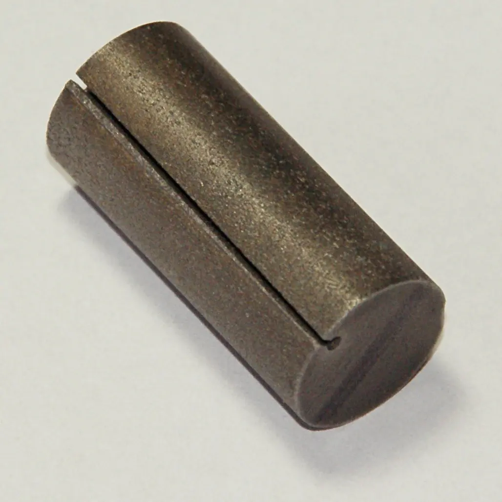 A short, dull gray metal cylinder with a slot cut along its length, lying on a white surface