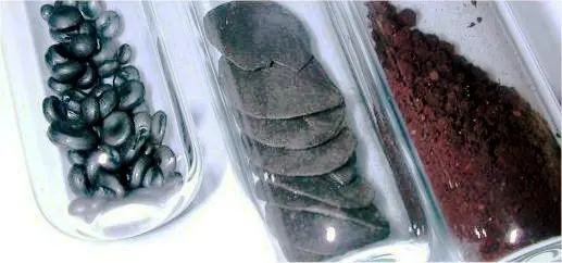 Three glass tubes side by side: one of shiny black beads, one of dull gray flakes, and one of dark red powder