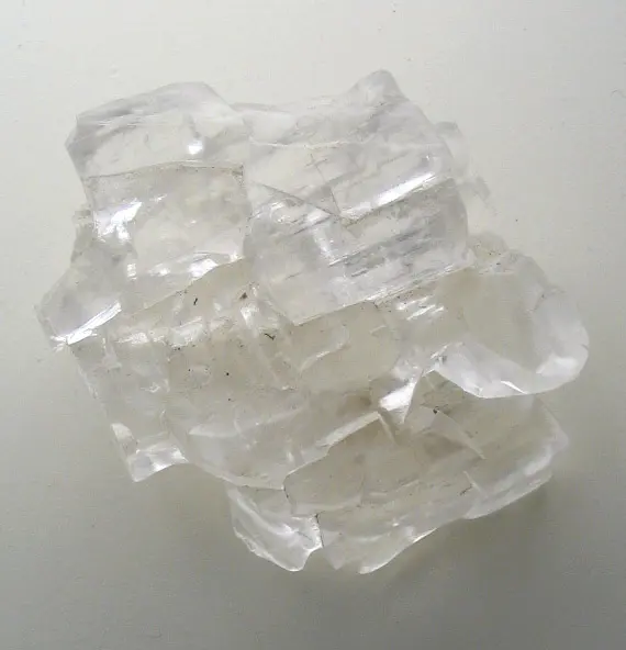 A cluster of clear, colorless crystals with flat faces and square-cornered steps