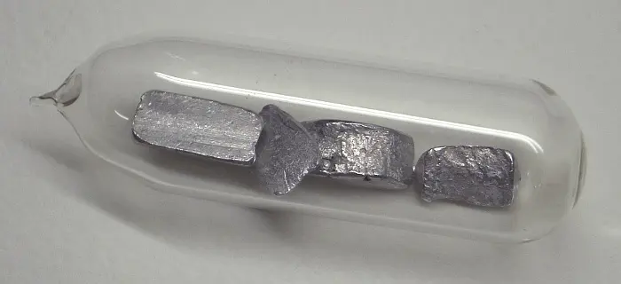Four small silvery-gray lumps of metal inside a sealed glass tube