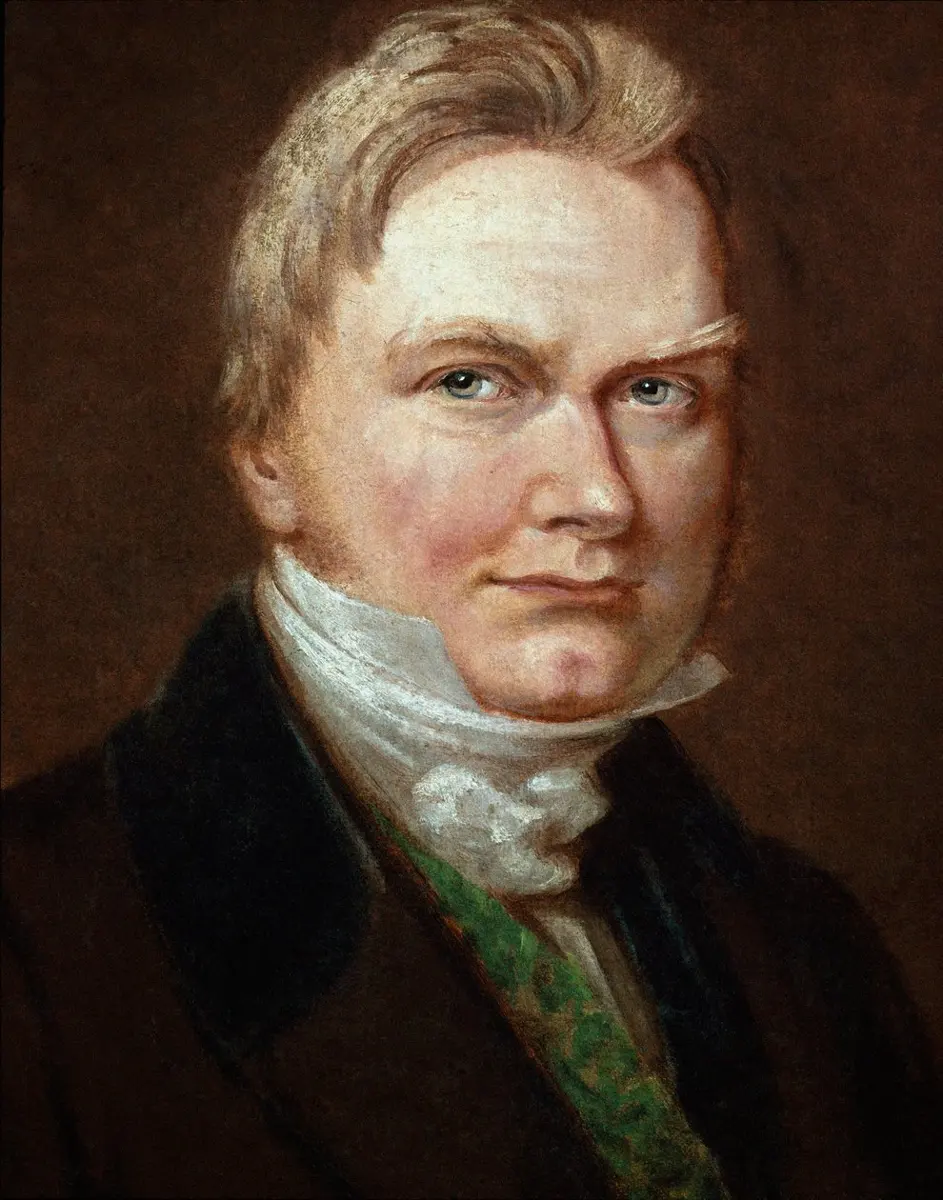 A painted portrait of a fair-haired man with blue eyes, in a dark coat, a green waistcoat and a white cravat