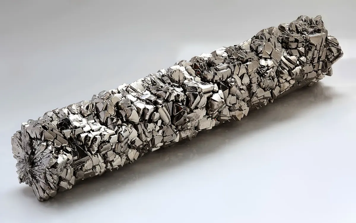 A bar of shiny silver-gray metal about as long as a hand, covered all over in small, sharp, flat crystals
