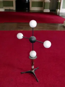 An old model on a stand: a black ball with four white balls on rods, all in one flat cross