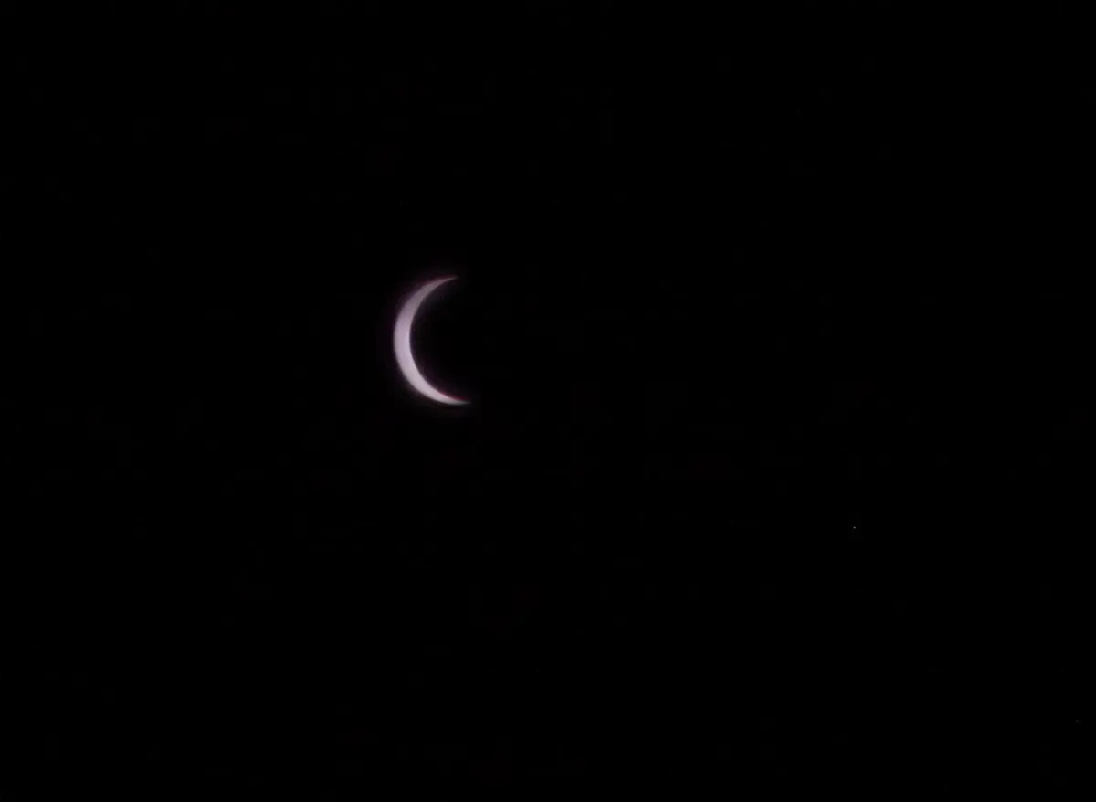 The Sun seen through a dark filter as a thin bright crescent against a black background, the rest of it hidden by the Moon