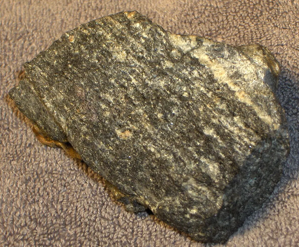 A fist-sized gray rock with faint light and dark streaks, lying on a towel