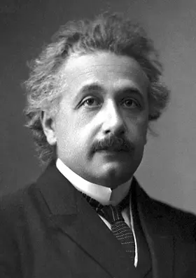 A black-and-white portrait photograph of Albert Einstein in his forties, with wavy hair and a mustache, wearing a suit and tie
