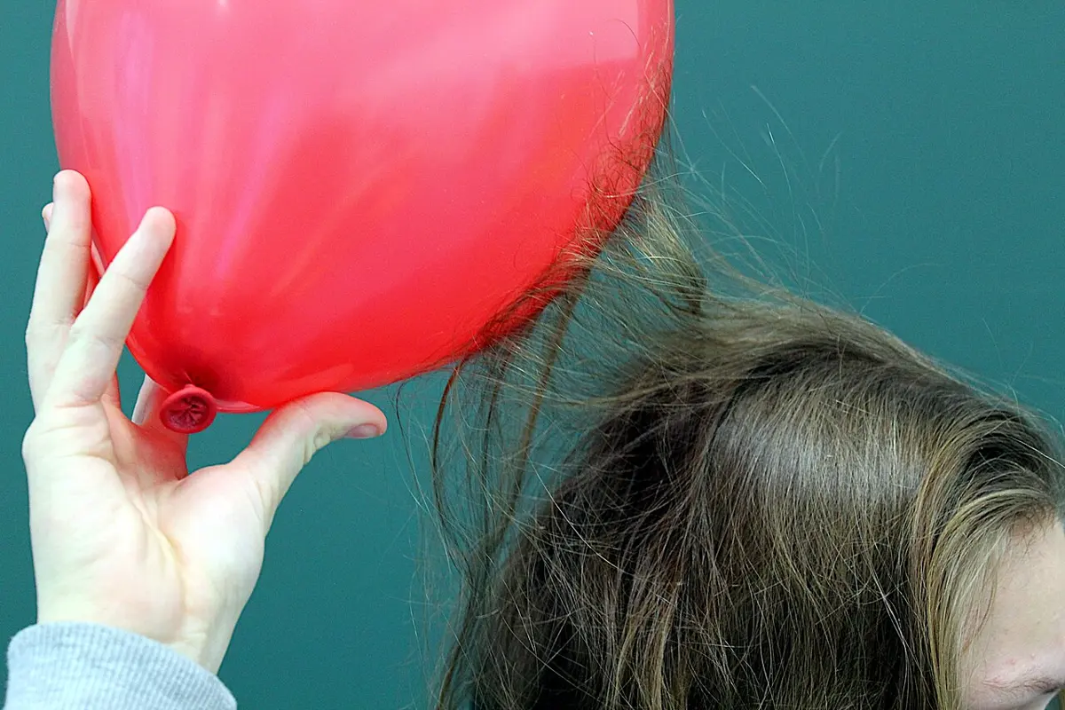 Long hair rising up from a person's head and clinging to a red balloon held just above it