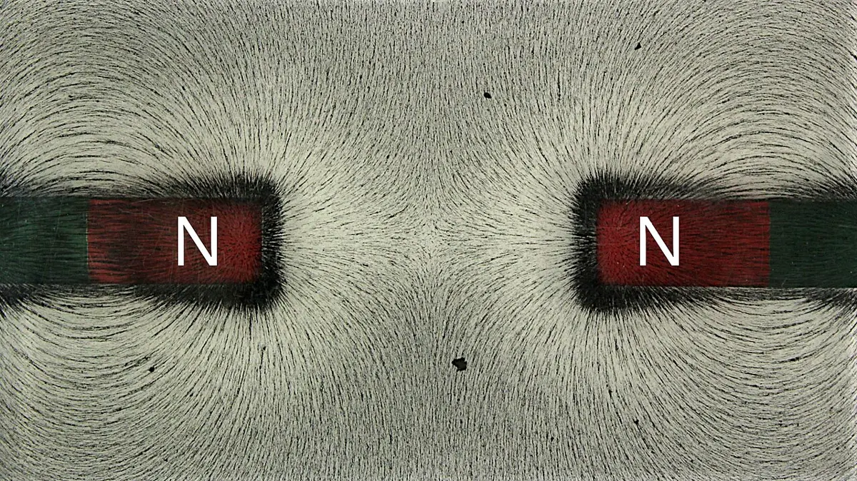 Iron filings on a white sheet over two bar magnets placed end to end, like poles facing; the filings between the magnets bend away sideways, and none runs from one magnet to the other