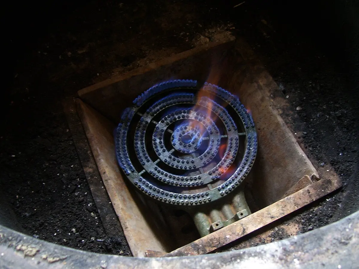 A round gas burner with rings of small blue flames, with a few orange streaks