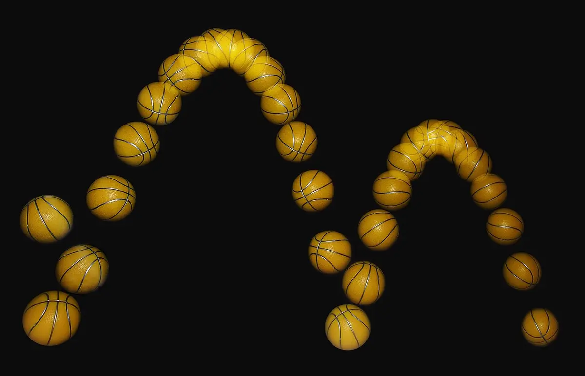 Many images of the same orange toy basketball on a black background, tracing two arches from left to right, the second lower than the first