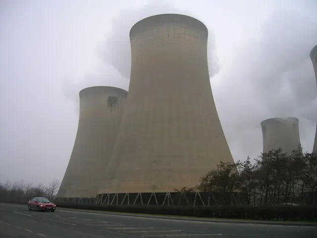 Huge concrete cooling towers, wider at the base and top than in the middle, with white clouds rising from them