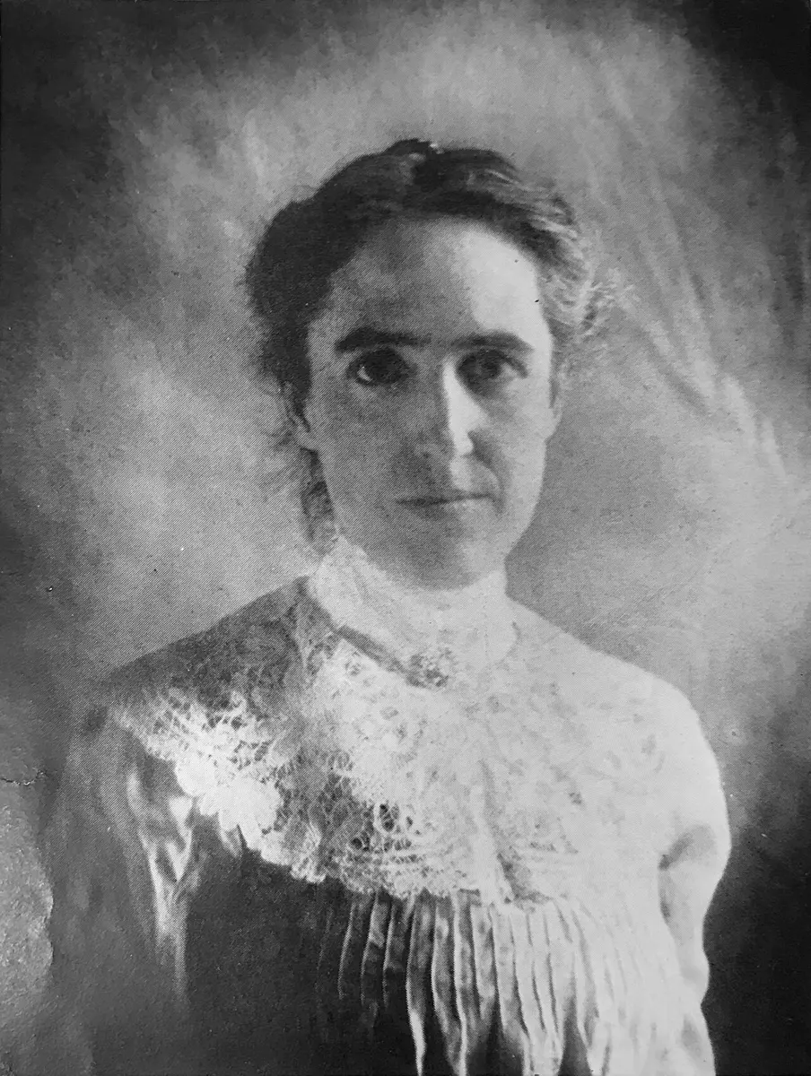 A black-and-white portrait photograph of a woman with her hair up, in a blouse with a wide lace collar