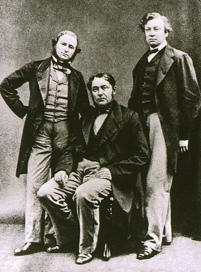 An old black-and-white photograph of three men in nineteenth-century suits, one seated between two standing