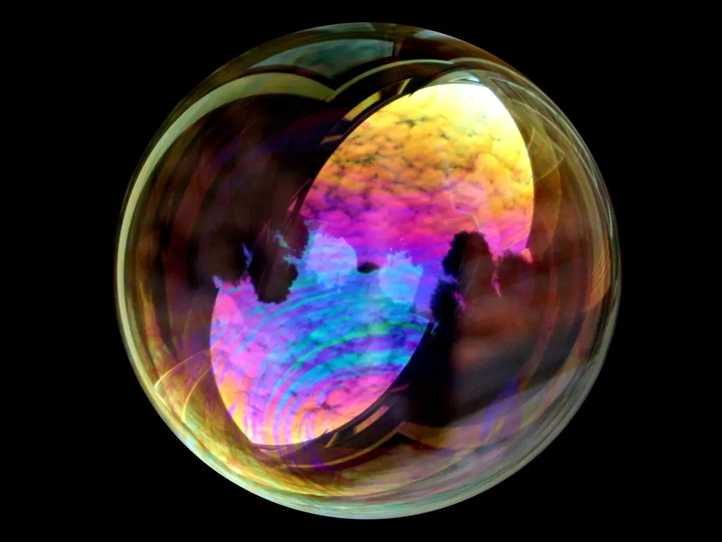 A soap bubble against a dark background, its skin shimmering with swirls of pink, gold, green and blue