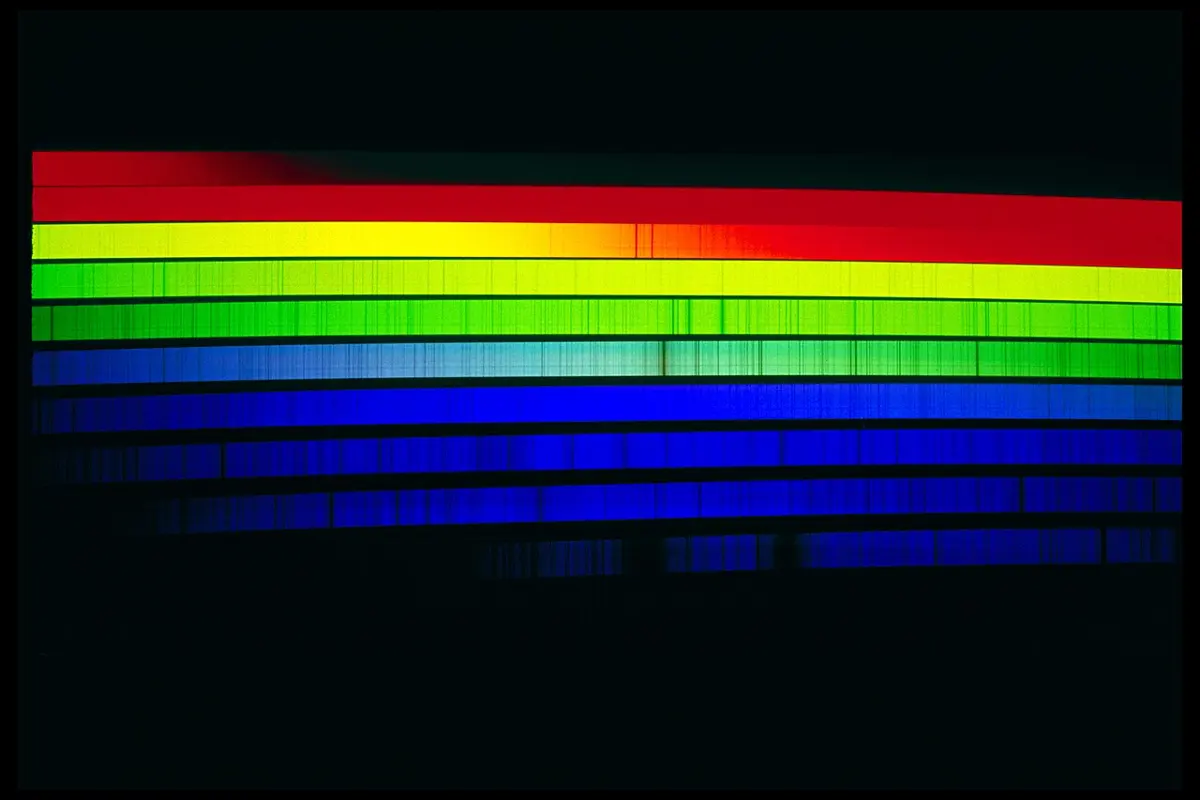 The Sun's visible spectrum cut into strips and stacked, red at the top to violet at the bottom, each strip crossed by many thin dark lines
